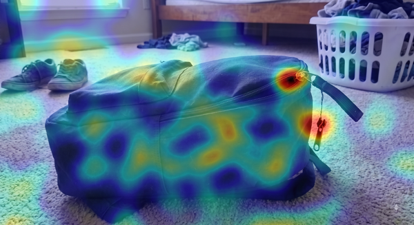 Navy backpack lying on carpet — forensic heatmap highlighting the AI-edited region