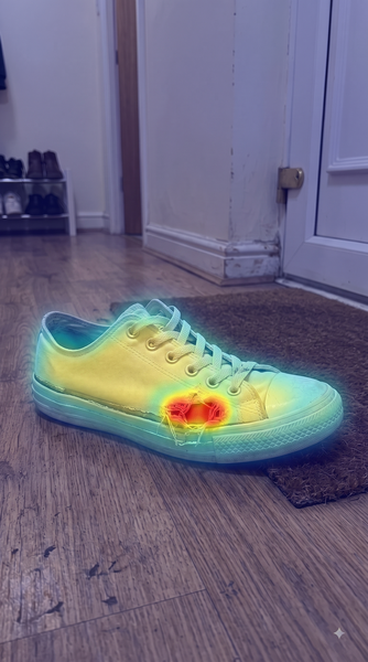 White canvas sneaker with a hole in the toe — forensic heatmap highlighting the AI-edited region