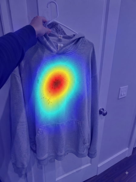 Grey hoodie on a hanger with brown stains — forensic heatmap highlighting the AI-edited region