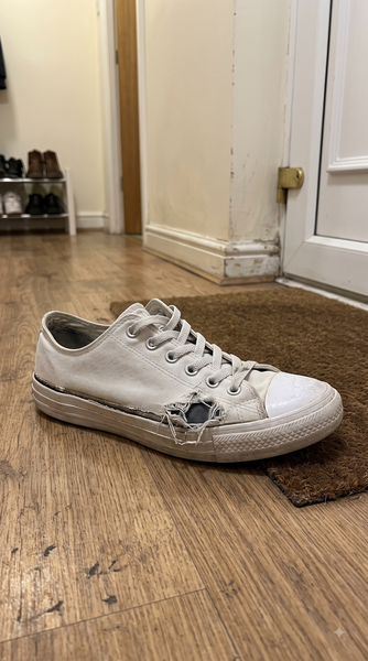 White canvas sneaker with a hole in the toe — the photo the customer submitted with their refund claim