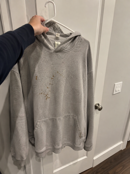 Grey hoodie on a hanger with brown stains — the photo the customer submitted with their refund claim